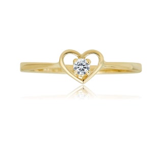 May include: A gold ring with a heart-shaped design and a single clear stone in the center.