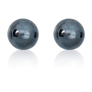 May include: A pair of black round stud earrings. The earrings are made of a smooth, shiny material.