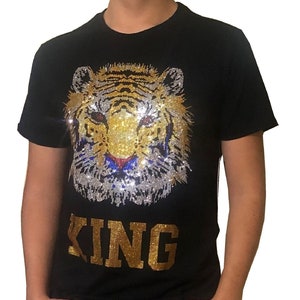 May include: Black t-shirt with a gold and silver sequined tiger head and the word "KING" in gold sequins.