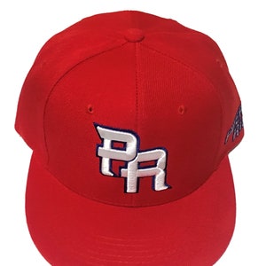 May include: A red baseball cap with a white "PR" logo embroidered on the front. The logo has a blue outline.