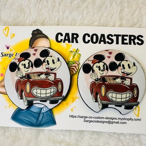 May include: Two car coasters featuring Mickey and Minnie Mouse in a vintage car. The coasters are round with a white background and a cartoon illustration. The words "CAR COASTERS" are printed at the top of the card.