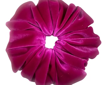May include: A large, bright pink velvet scrunchie for hair.