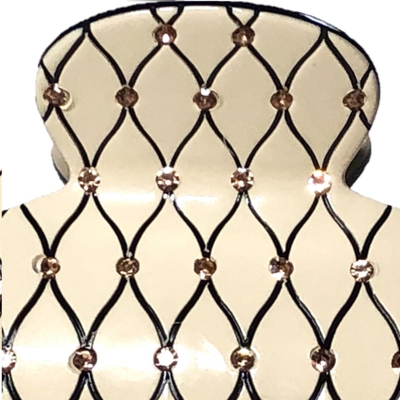 Puede incluir: Una pinza para el pelo blanca con un patr&oacute;n de diamante blanco y negro y diamantes de imitaci&oacute;n transparentes.