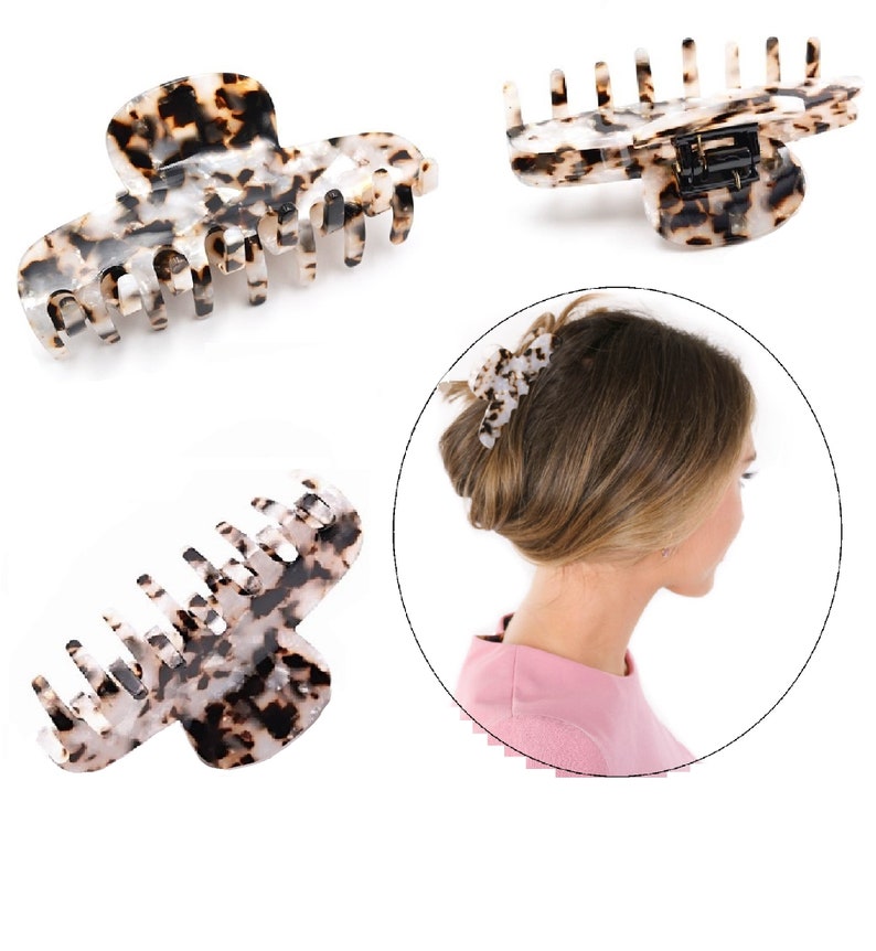 Puede incluir: Una pinza para el cabello con un patr&oacute;n de carey en colores moteados negro, marr&oacute;n y blanco. La pinza tiene una serie de dientes entrelazados y un mecanismo de bisagra con resorte. El dise&ntilde;o se muestra desde varios &aacute;ngulos y en uso.