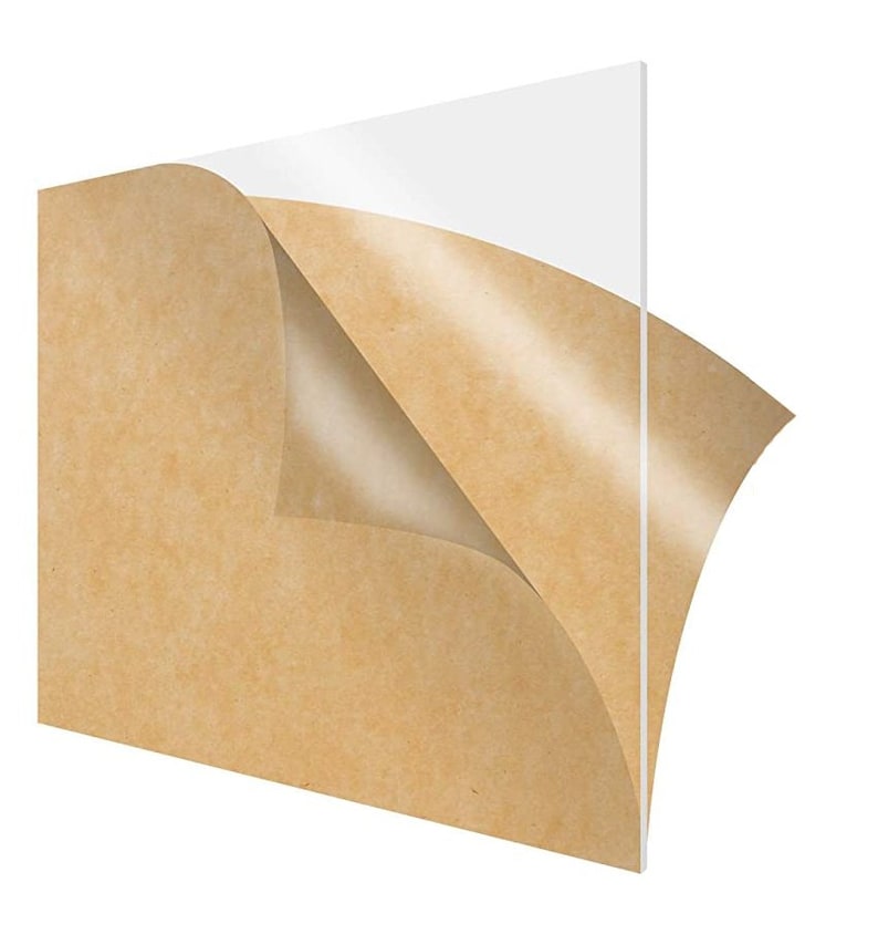 May include: A clear acrylic sheet with a protective brown paper backing. The paper is partially peeled back to reveal the smooth, transparent surface of the acrylic.