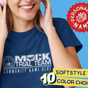 Pode incluir: Uma camiseta azul marinho com texto branco que diz "MOCK TRIAL TEAM" e "COMMUNITY NAME HERE". A camiseta é uma camiseta softstyle e está disponível em 10 cores.