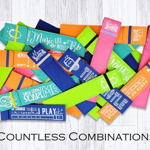 May include: A collection of colorful fabric pencil cases with various designs and text, including "Music Life", "You Can't Scare Me", "Of Course I Play It", "Noise", "Tin Castle", and "Parts Of A Flute".