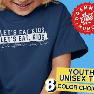 May include: A navy blue youth unisex t-shirt with the text "LET'S EAT KIDS. LET'S EAT, KIDS. Punctuation saves lives." in white lettering. The shirt is a youth size and is available in 8 colors.