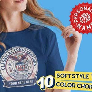May include: Navy blue t-shirt with a circular graphic featuring an eagle, scroll, and the text "CLASSICAL CONVERSATIONS." The shirt includes the text "YOUR NAME HERE" and "SOFTSTYLE TEE!" with "10 COLOR CHOICES" on a yellow banner. A red starburst reads "PERSONALIZE the NAME!"