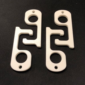 May include: Two white plastic door openers with a variety of shapes for opening doors and pushing buttons. The openers are designed to help avoid touching surfaces in public places.