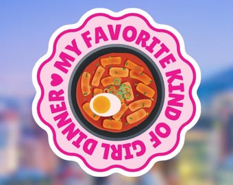 May include: A pink sticker with the text "Dinner My Favorite Kind Of Girl" encircling a bowl of Korean tteokbokki. The tteokbokki is in a red sauce with a boiled egg and green onions.