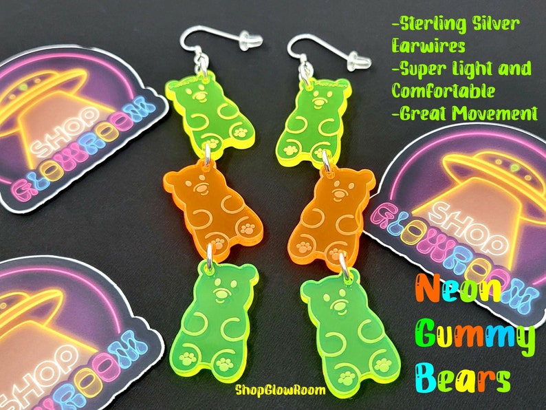 May include: Neon green, orange, and yellow gummy bear shaped earrings with sterling silver ear wires. The earrings are hanging from a white background with a neon sign that says "Shop Glow Room" and a UFO.