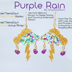May include: Purple Rain earrings with gold filled hooks and gold plated jump rings. The earrings feature a cloud with gold glitter and a lightning bolt with purple raindrops.