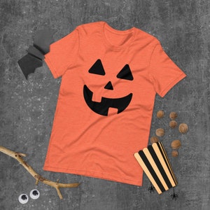 May include: Orange t-shirt with a black jack-o'-lantern face graphic.