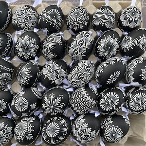 Könnte beinhalten: Eine Sammlung schwarzer Ostereier, die mit komplizierten weißen Mustern verziert sind. Die Eier sind in einem Eierkarton aus Pappe angeordnet.