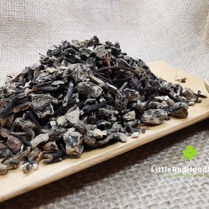 Op de afbeelding: Een hoop gedroogde zwarte en bruine wortels en kruiden op een houten oppervlak. De kruiden zijn in een hoop gelegd en klaar om te worden gebruikt voor het maken van thee of andere kruidenremedies.