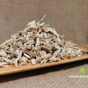 May include: A pile of dried, light brown and white, wood chips on a wooden surface. The chips are irregularly shaped and have a rough texture.