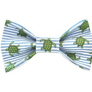 May include: A blue and white striped bow tie with a pattern of green sea turtles.