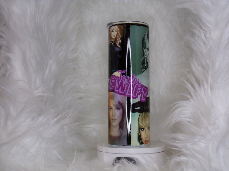 May include: A stainless steel tumbler with a black and green design featuring multiple images of Taylor Swift. The tumbler has a pink "Taylor Swift" logo.