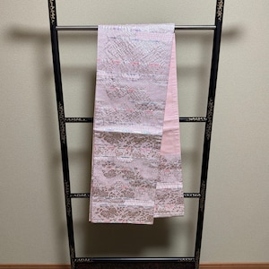 Könnte beinhalten: Ein schwarzer Holzständer für Kimonos mit einem rosa und silbernen Kimono, der daran hängt.