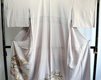 May include: A light lavender kimono featuring wide sleeves and a floor-length hem. The lower section is decorated with intricate, multi-colored floral and geometric patterns in shades of gold, green, white, and brown, set against the solid fabric.