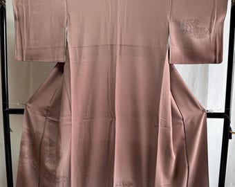 May include: A mauve silk kimono with embroidered floral designs. The kimono is hanging on a black wooden hanger.