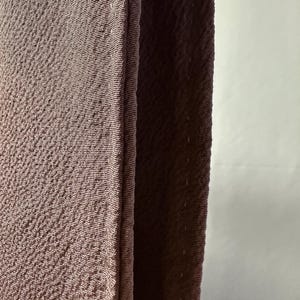 K&ouml;nnte beinhalten: Nahaufnahme eines braunen Stoffes mit strukturierter Oberfl&auml;che. Der Stoff ist in der Mitte gefaltet und die Kanten sind zusammengen&auml;ht.