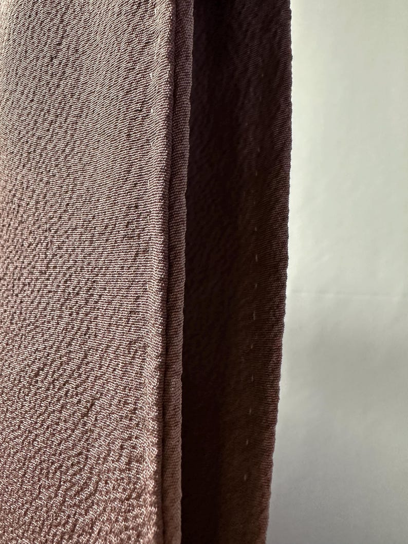 K&ouml;nnte beinhalten: Nahaufnahme eines braunen Stoffes mit strukturierter Oberfl&auml;che. Der Stoff ist in der Mitte gefaltet und die Kanten sind zusammengen&auml;ht.
