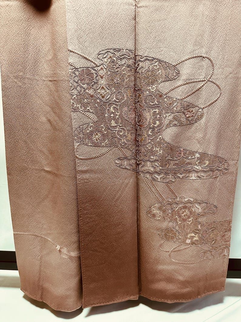 K&ouml;nnte beinhalten: Ein braunes Seidenkimono mit traditionellem japanischem Design. Das Design zeigt ein stilisiertes Blumenmuster in Gold- und Silberfaden.