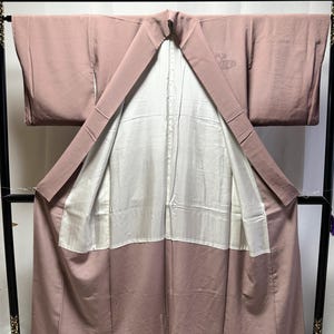 K&ouml;nnte beinhalten: Ein mauvefarbener Kimono mit wei&szlig;em Futter und einem kleinen gestickten Schmetterlingsmuster auf der R&uuml;ckseite.