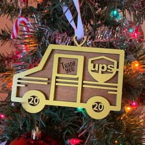 Könnte beinhalten: Ein gelber Holzschmuck in Form eines UPS-Lieferwagens mit den Worten "Thank You" und "ups" an der Seite. Der Schmuck hat die Nummer "20" an jedem Rad.