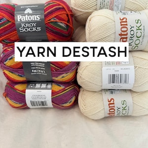 May include: A collection of yarn balls in various colors, including red, orange, yellow, green, purple, and white. The yarn is labeled "Patons Kroy Socks" and "Yarnspirations".