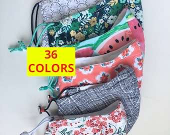 May include: Five different fabric face masks with various patterns, including floral, geometric, and watermelon. The masks are stacked on top of each other. A yellow label with the text "36 COLORS" is visible in the image.