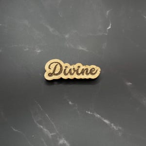 May include: A wooden sign with the word "Divine" engraved in a cursive font.