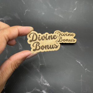 May include: Two wooden signs with the text "Divine Bonus" in a cursive font. The signs are brown and have a slightly rough texture.