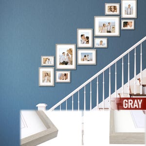 Puede incluir: Una colecci&oacute;n de fotograf&iacute;as enmarcadas de varios tama&ntilde;os dispuestas en una pared azul. Los marcos son de color gris claro y las fotos parecen ser de una pareja. La disposici&oacute;n est&aacute; encima de una escalera blanca.
