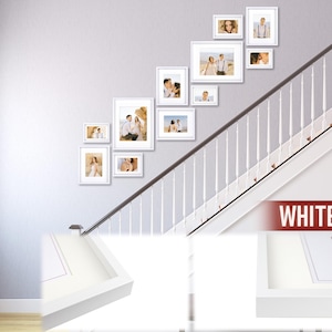 Puede incluir: Una colecci&oacute;n de marcos de fotos blancos de varios tama&ntilde;os dispuestos en una pared gris, ascendiendo por una escalera. Los marcos contienen fotograf&iacute;as de personas. La palabra "WHITE" se muestra en una pancarta roja.