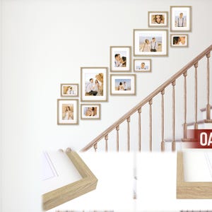 Puede incluir: Una colecci&oacute;n de fotograf&iacute;as enmarcadas de varios tama&ntilde;os dispuestas en una pared blanca. Los marcos son de color roble claro y las fotos muestran personas. La palabra "OAK" es visible en la esquina inferior derecha.
