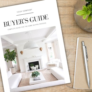May include: A white and gray home buyer's guide with the text "Buyer's Guide" in black and the text "Complete Guide for the Home Buying Process" in smaller black text. The cover features a photo of a white living room with a fireplace, a white sofa, and a large white pendant light.