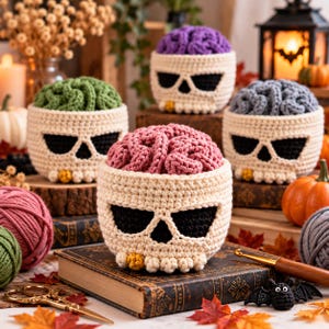 Peut inclure: Quatre bols crochetés en forme de crâne, surmontés d'une structure texturée en forme de cerveau de couleur verte, violette, grise ou rose. Les crânes blanc cassé présentent des orbites noires et un petit accent jaune près des dents.