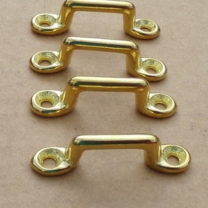 May include: Four gold-colored metal loop handles with a rounded rectangular shape. The handles have a smooth, polished finish.
