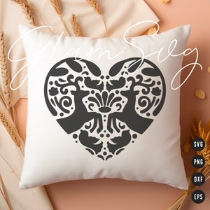 May include: A white pillow with a black heart-shaped design featuring two stylized deer with floral patterns. The design is reminiscent of Scandinavian folk art.