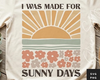 May include: Cream-colored t-shirt with a retro graphic design. The design features a stylized sun, a horizontal stripe, and floral elements, with the text "I WAS MADE FOR SUNNY DAYS" in a bold font. The shirt is made of a soft material.