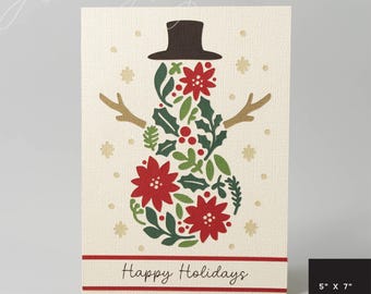 May include: A cream-colored holiday card featuring a snowman design made of red poinsettias, green leaves, and a brown top hat and twig arms. The card reads "Happy Holidays" in a red banner. The card measures 5" x 7".