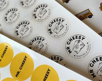 May include: A sheet of white stickers with black and white circular labels that say "Mr. Cheesy" with the text "Toasties & Fries" underneath. There are also yellow circular stickers that say "Mr. Cheesy" in black text.