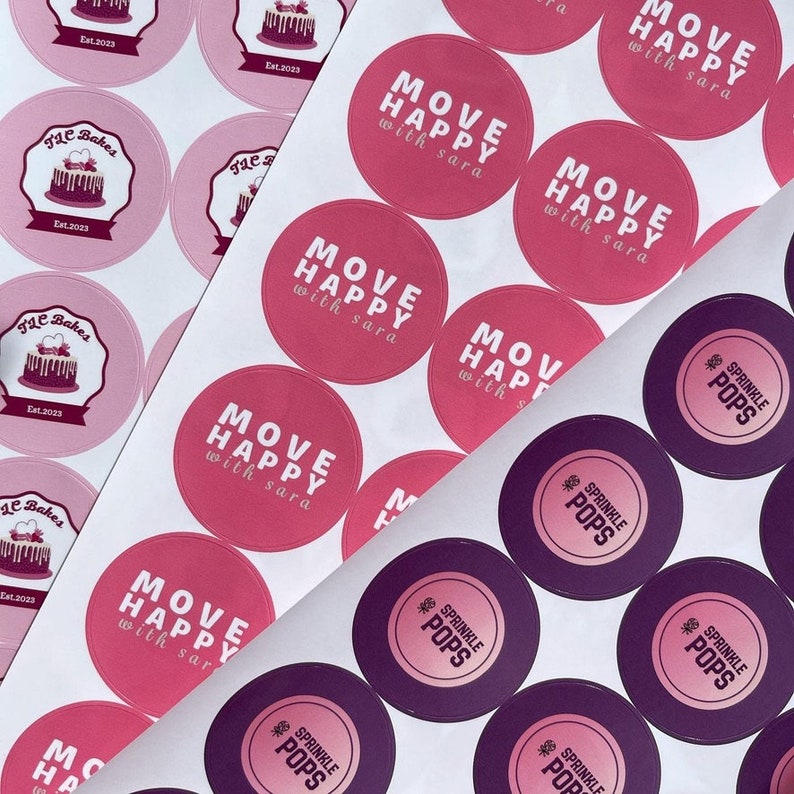 May include: Assortment of pink and purple round stickers with various designs. The pink stickers feature the text "MOVE HAPPY with sara" in white. The purple stickers feature the text "SPRINKLE POPS" in white with a pink star.