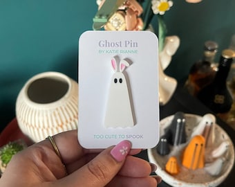 May include: White ghost pin with pink bunny ears. The pin says "Ghost Pin by Katie Rianne" and "Too Cute to Spook".