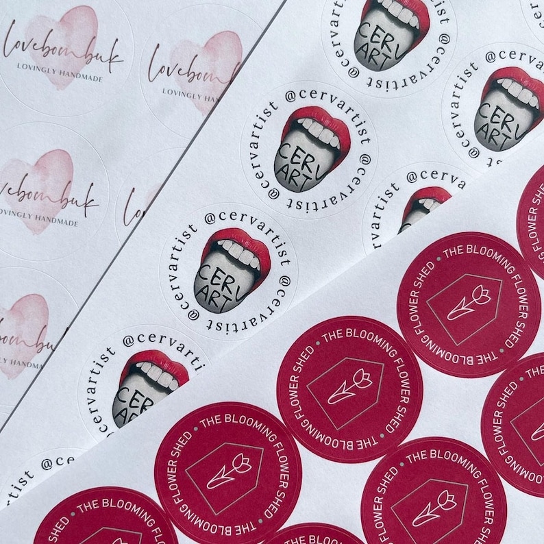 May include: Assortment of round stickers with various designs. Some stickers feature a pink heart with the text "loveboonbuk" and "lovingly handmade". Other stickers feature a red mouth with a tongue sticking out and the text "CERV ART" and "@cervartist".  A few stickers feature a red tulip with a stem and the text "THE BLOOMING FLOWER SHED".