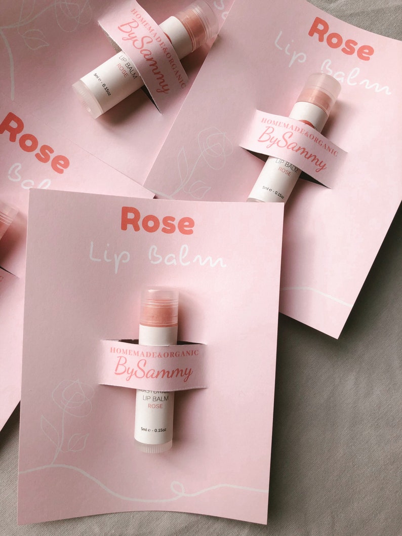May include: Three pink and white labels with the text "Rose Lip Balm" and "Homemade & Organic By Sammy" on them. Each label has a small tube of lip balm with a pink and white label that says "Lip Balm Rose" and "Homemade & Organic By Sammy".