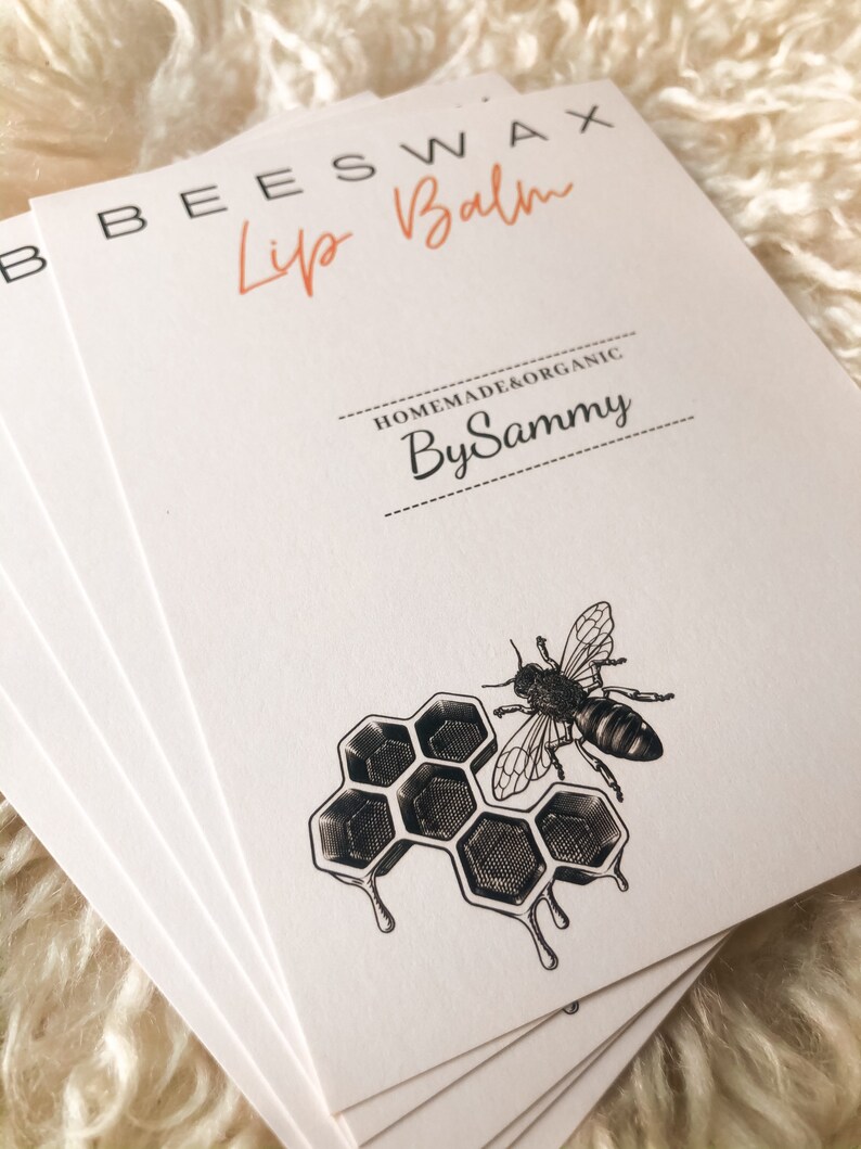 Op de afbeelding: Een stapel witte kaarten met zwarte tekst die "Beeswax Lip Balm Homemade & Organic By Sammy" luidt. De onderste kaart toont een zwart-witte illustratie van een honingraat met een bij.